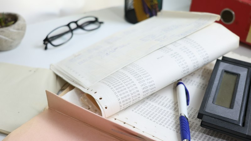 A desk with documents, glasses and a calculator