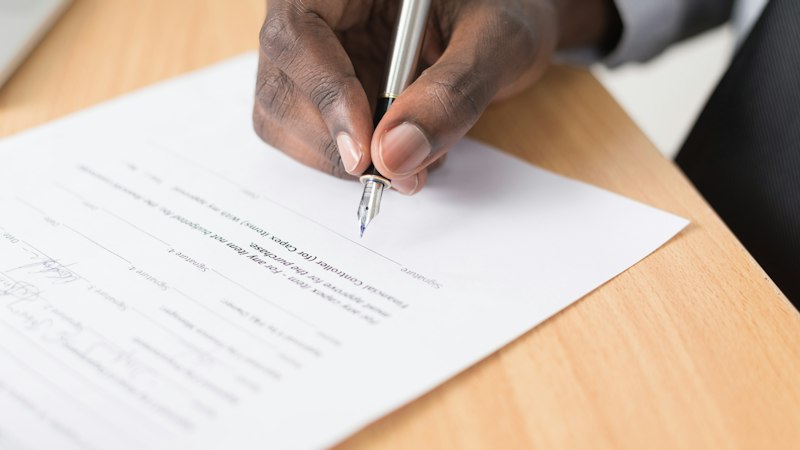 Firma de un documento sobre la mesa de un despacho